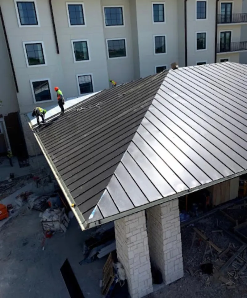 Crew installing standing seam metal roof panels on a commercial project in Plainview